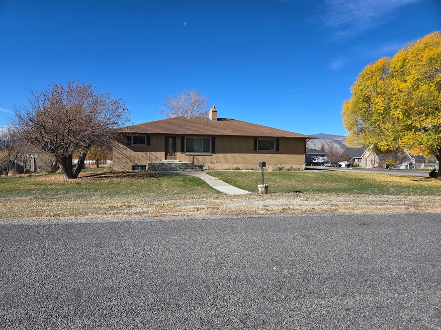 Single story home with a front lawn, brick siding, a chimney, and a mountain view
