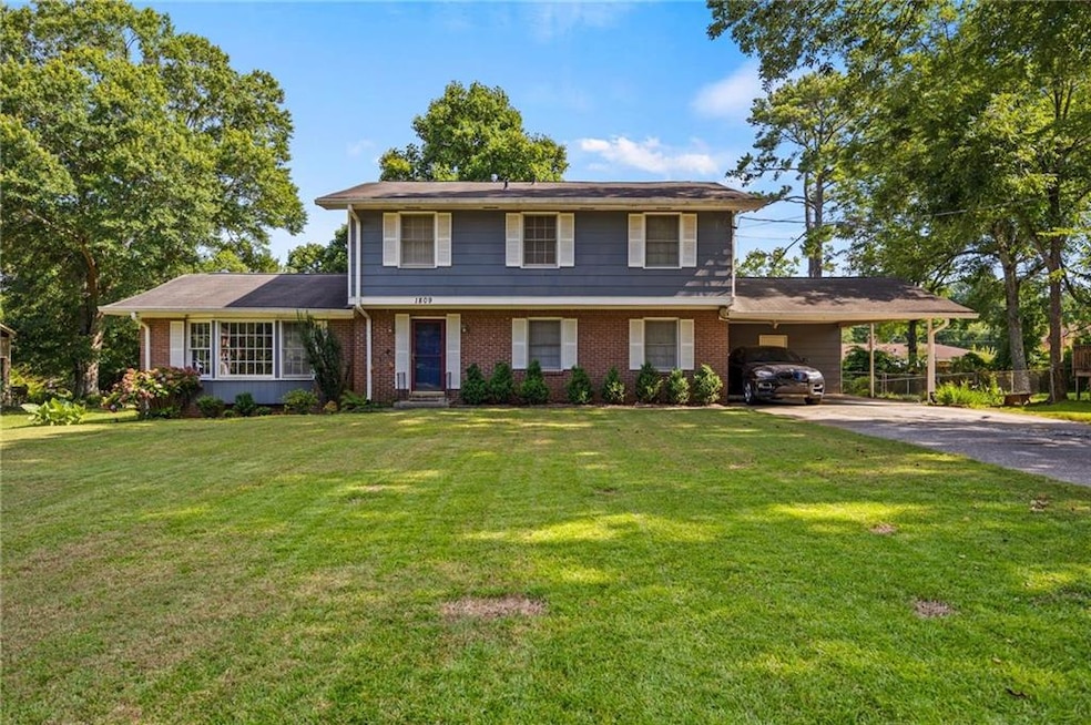 View of front facade featuring concrete driveway, brick siding, and a carport