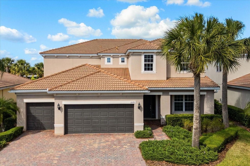 Welcome to 12173 Aztec Rose Lane - where timeless Mediterranean style meets modern elegance. With its classic terracotta tile roof, brick-paved drive, and canopy of mature palms, this striking exterior sets the tone for the casual Florida luxury that awaits inside. Located within VillageWalks's exclusive guard-gated enclave, enjoy  serene canal views, lush green spaces and resort-style living in one of Lake Nona's most coveted communities.