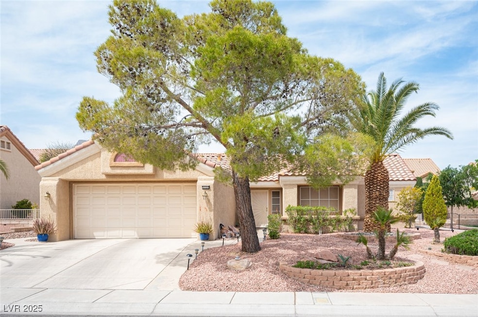 View of front of property with a tiled roof, stucco siding, fence, an attached garage, and driveway