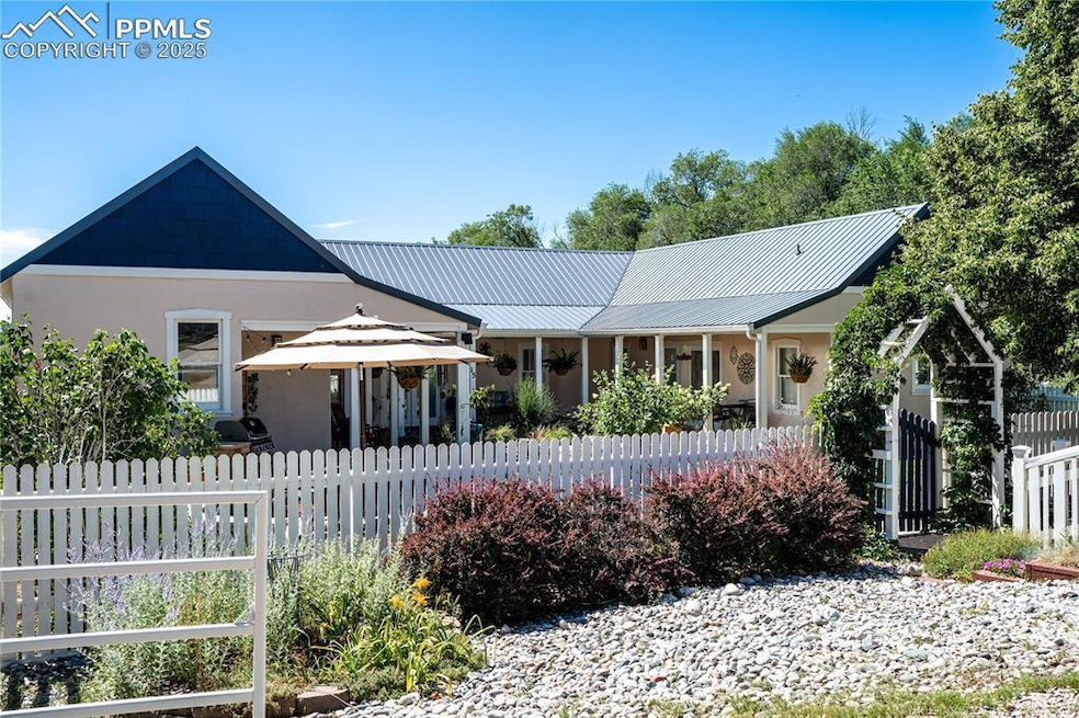 View of front of house with stucco siding, a fenced front yard, and metal roof