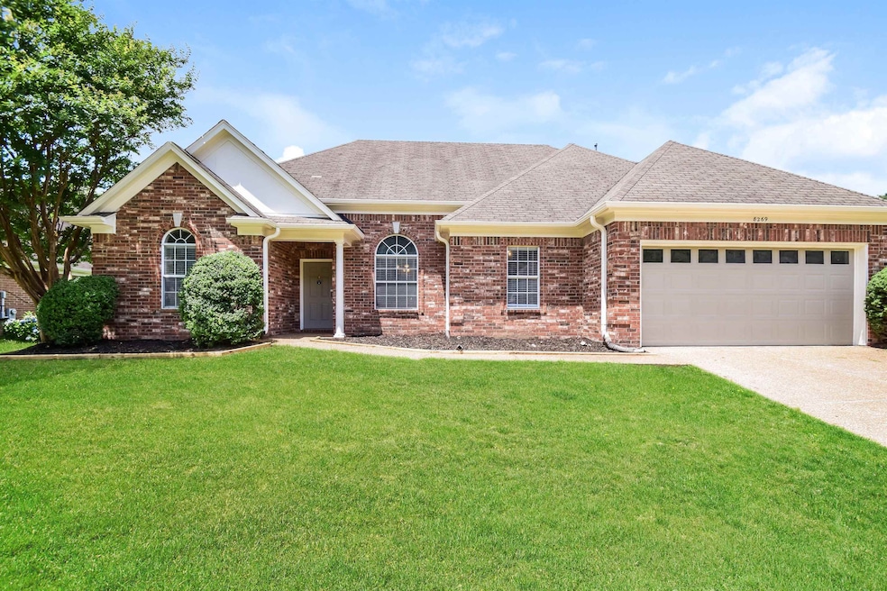 View of front of property with a front yard, an attached garage, driveway, and brick siding