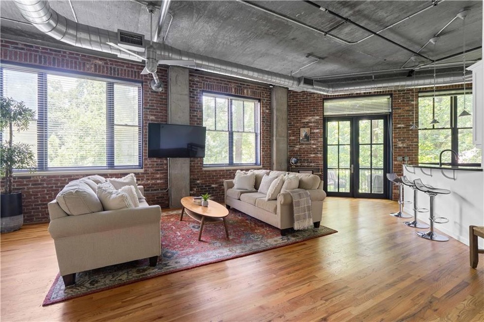 Living area featuring brick wall and wood finished floors
