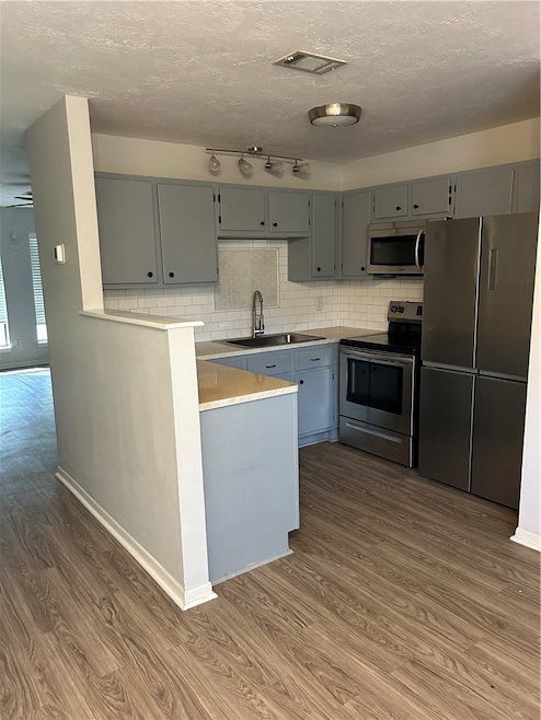 Kitchen featuring stove, a sink, fridge, gray cabi