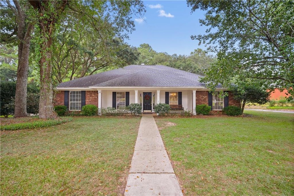 Ranch-style house with a porch, a front yard, roof with shingles, and brick siding
