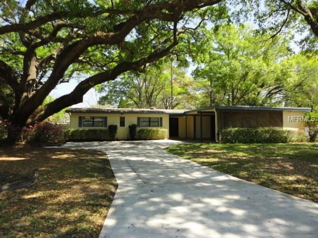 Mid-Century home nestled amongst giant oak trees and tropical foliage