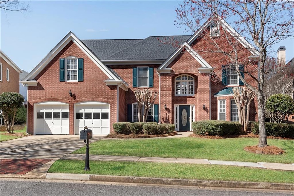 View of front of home with an attached garage, driveway, brick siding, a front yard, and a shingled roof