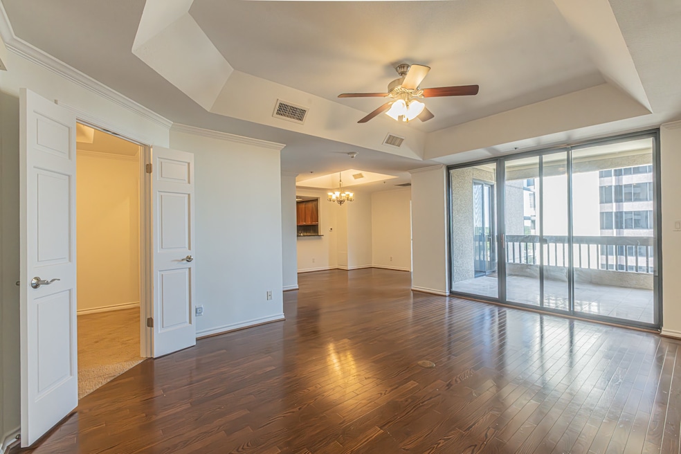 Spare room with a tray ceiling, floor to ceiling windows, a chandelier, dark wood-style flooring, and a ceiling fan