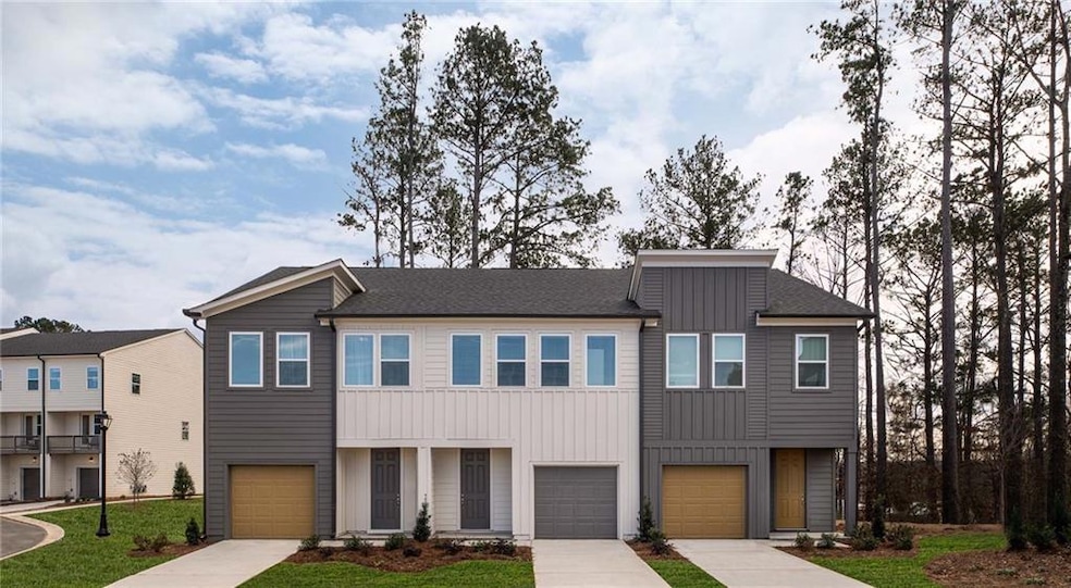 View of property with board and batten siding, an attached garage, driveway, and a front yard