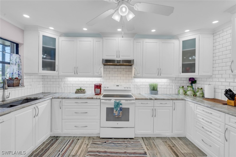 Kitchen with white electric stove, white cabinets,