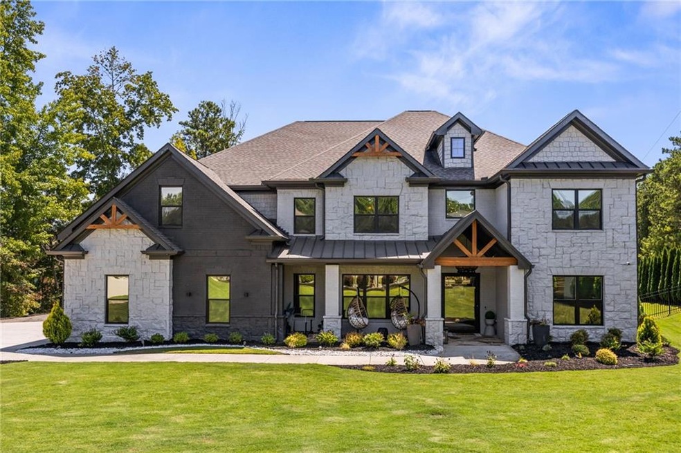 View of front facade with stone siding, a standing seam roof, a metal roof, and a front lawn