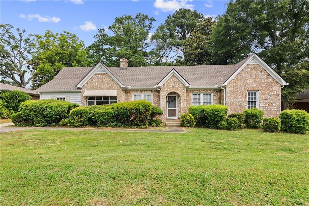 Single story home featuring a chimney, a front yard, brick siding, and roof with shingles