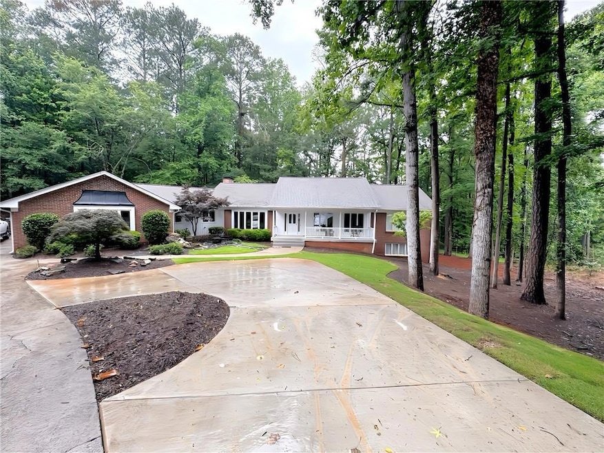 View of front of house with roof with shingles, a porch, brick siding, and a chimney