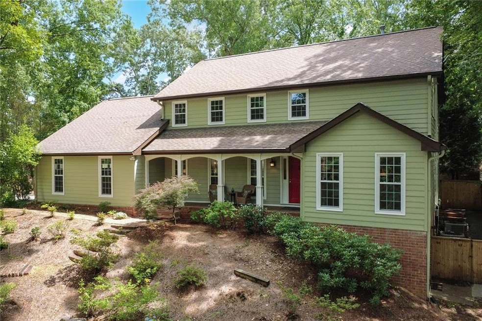 View of front of property featuring covered porch, brick siding, and a shingled roof