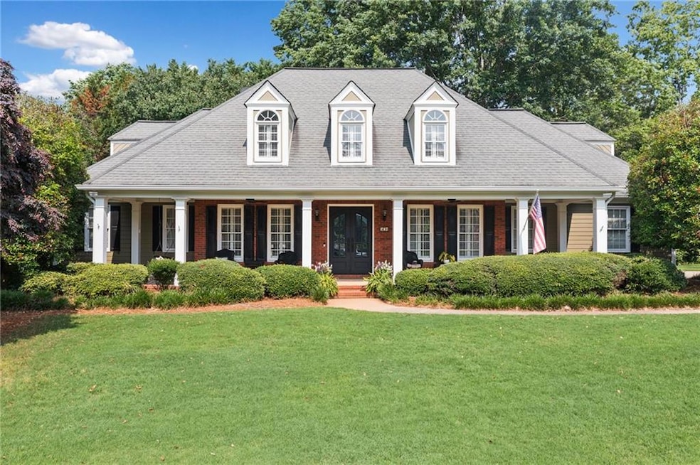 Cape cod-style house featuring covered porch and a front lawn