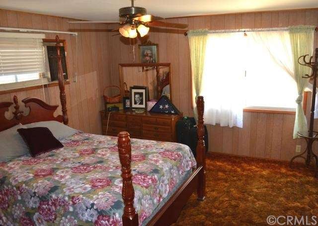 Wood paneling in 4th bedroom with built in shelves and ceiling fan.