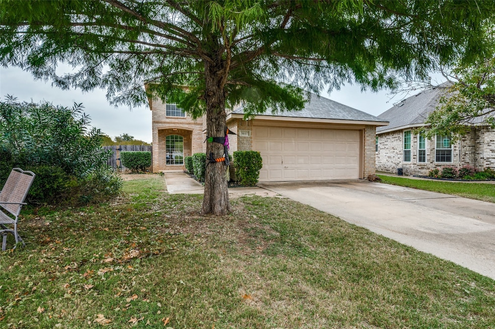 View of front facade with brick siding, driveway, roof with shingles, a front yard, and a garage