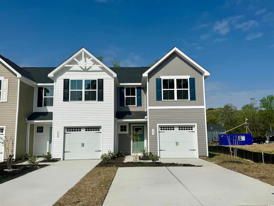 View of front facade with driveway, fence, and an 