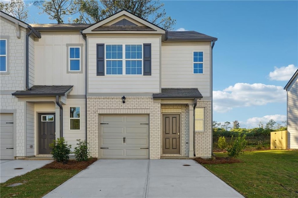 View of property with a garage, brick siding, boar