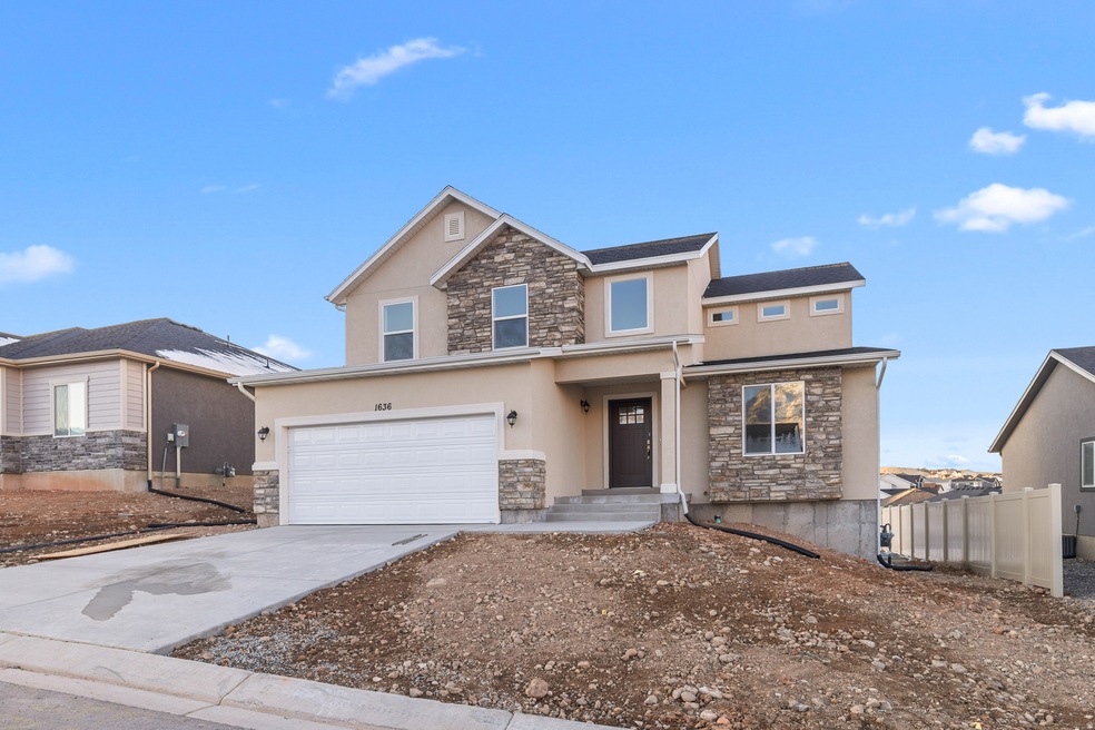 View of front facade featuring stone siding, stucco siding, concrete driveway, and an attached garage