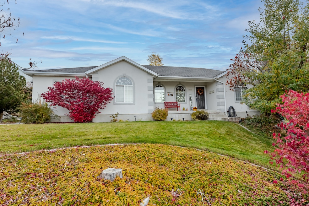 Ranch-style house with a porch, a front yard, stucco siding, and a shingled roof