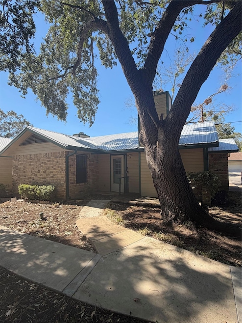 View of front of property featuring brick siding, a metal roof, and a chimney