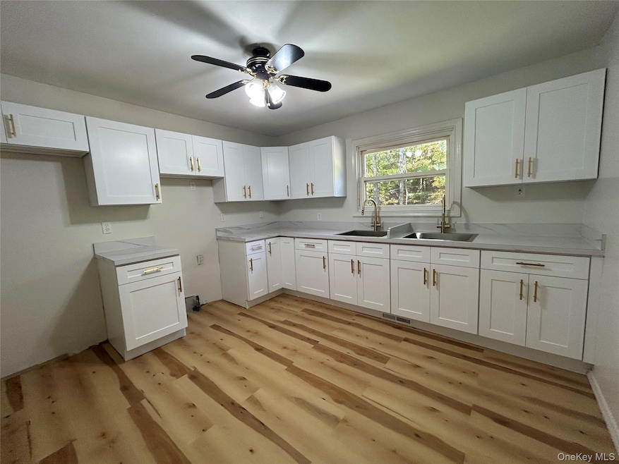 Kitchen with white cabinets, a ceiling fan, and light wood-type flooring