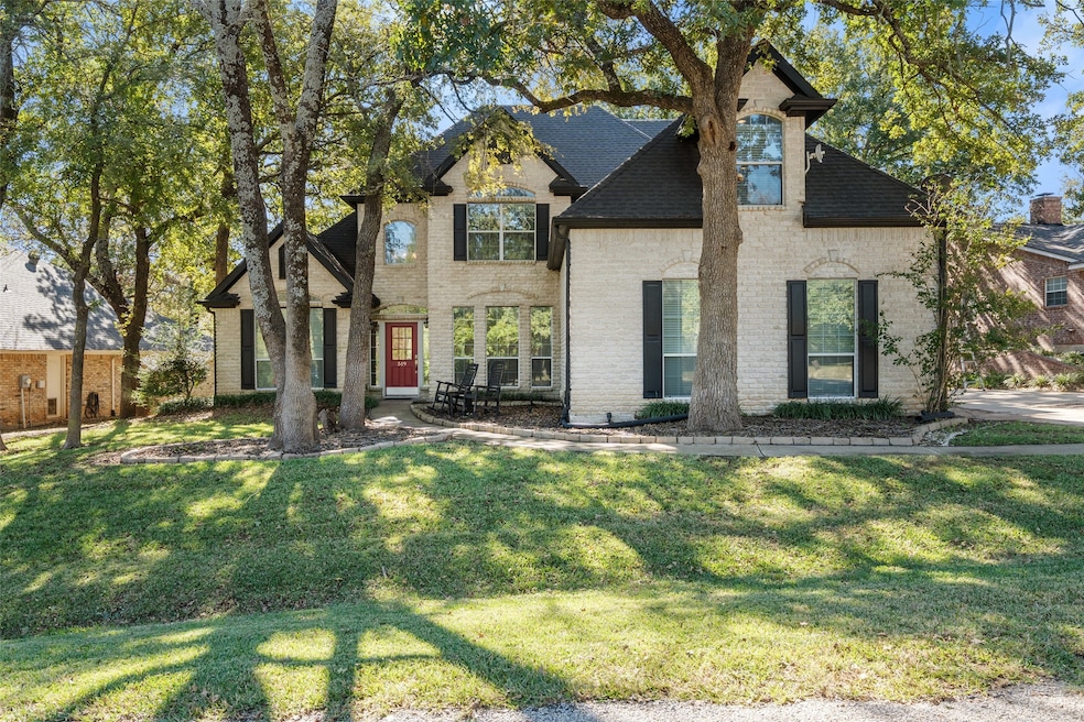 View of front of home with brick siding, a front lawn, and roof with shingles