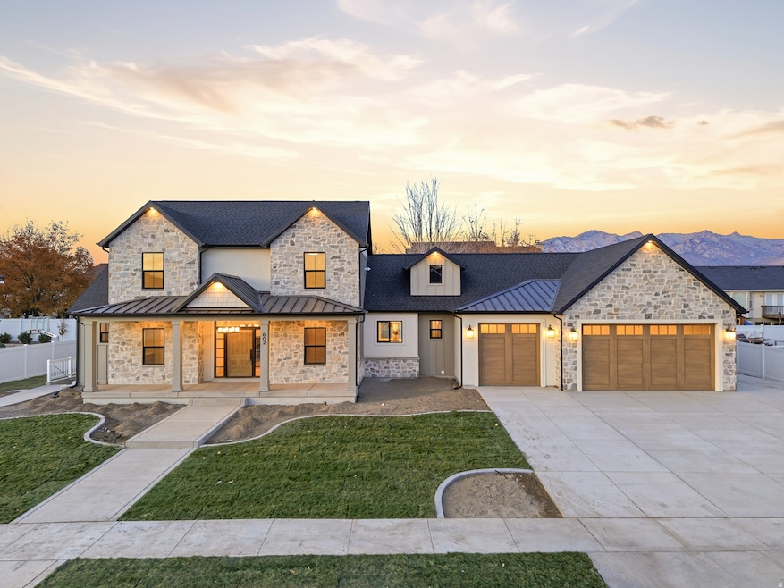 View of front of house with a standing seam roof, a metal roof, a porch, a garage, and stone siding