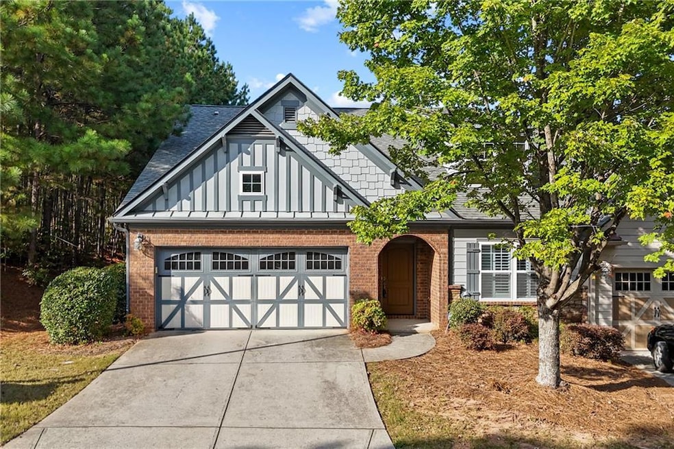 View of front of home featuring board and batten siding, a garage, concrete driveway, and brick siding