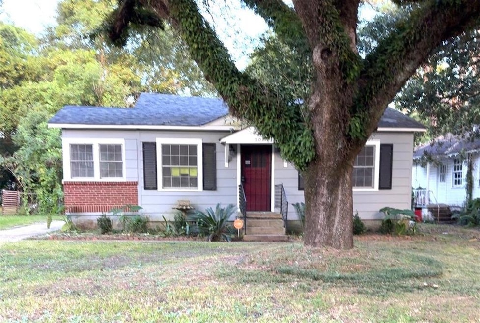 Bungalow-style home with a front yard, a shingled roof, and entry steps