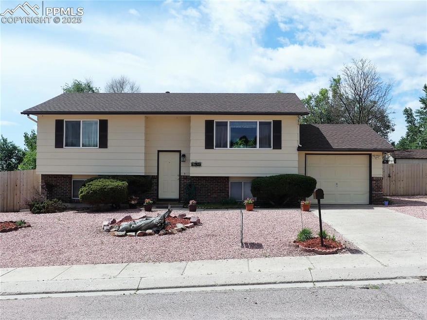 Bi-level home with an attached garage, concrete driveway, and brick siding