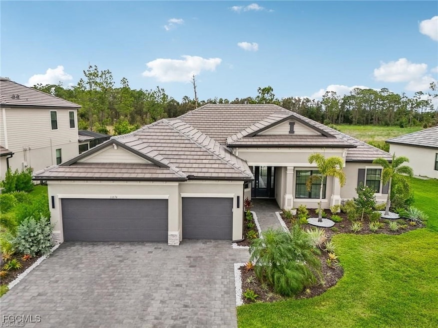 View of front of house featuring a front lawn, stucco siding, decorative driveway, a garage, and a tile roof