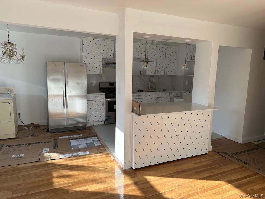 Kitchen featuring decorative backsplash, stainless steel appliances, washer / dryer, and light wood-style floors