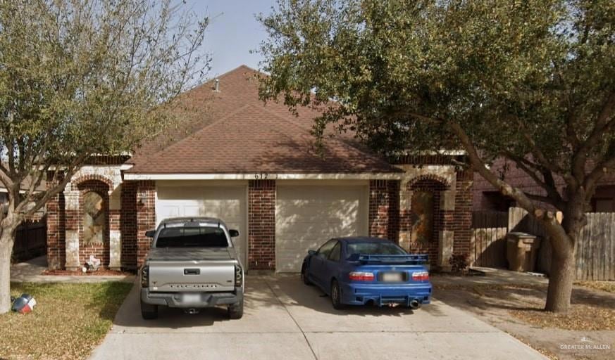 View of front facade featuring driveway, brick siding, and an attached garage