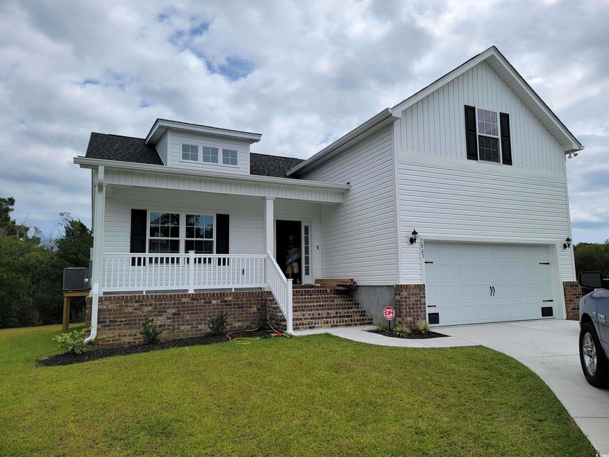 View of front of home with a front yard, covered p