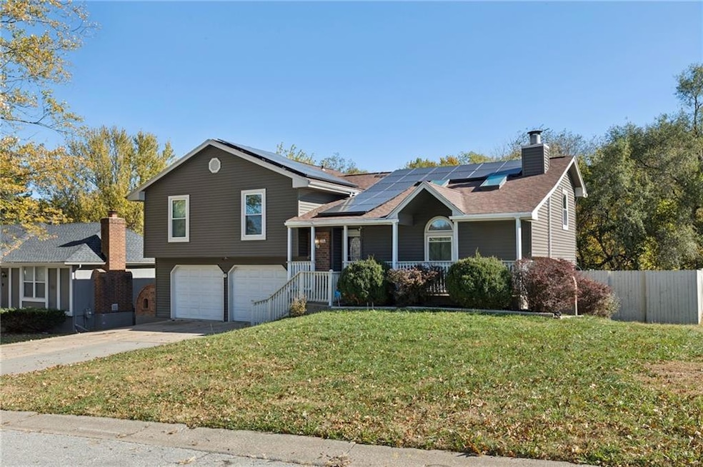 Split level home with roof mounted solar panels, concrete driveway, a porch, and an attached garage. Low utiltiy bills!
