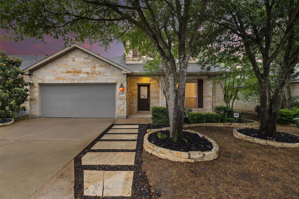 View of front facade with stone siding, a garage,