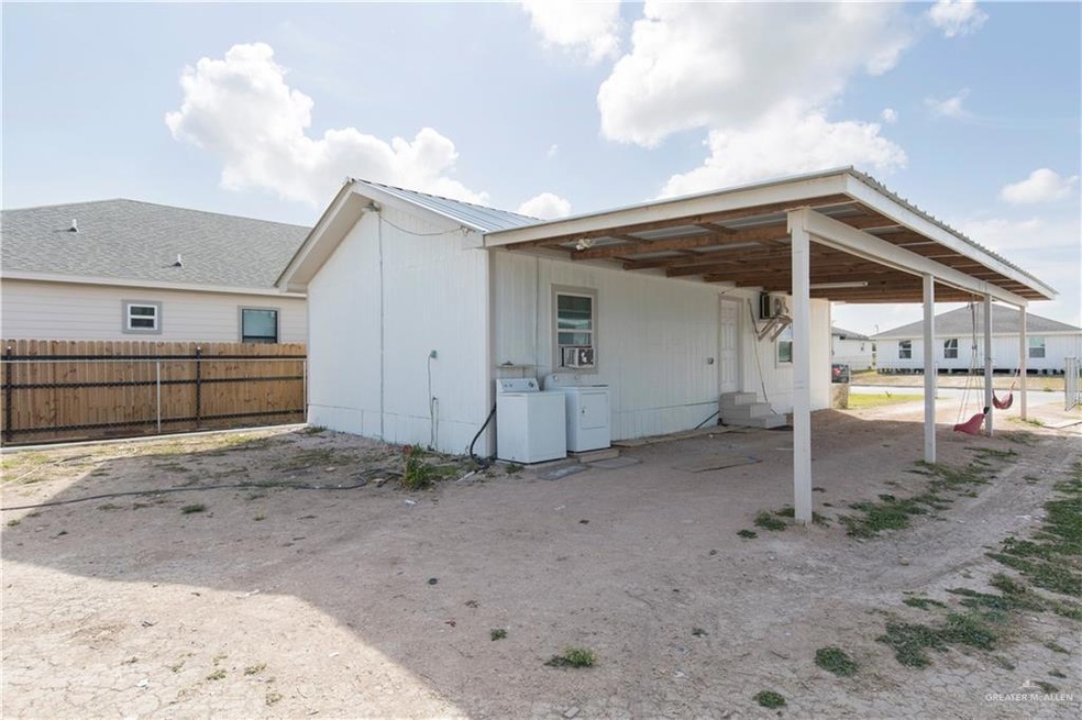 Rear view of property featuring an attached carport, fence, and separate washer and dryer