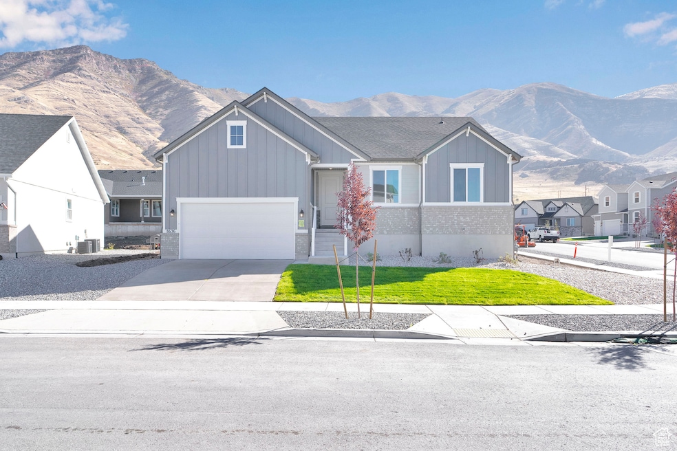 View of front facade featuring a mountain view, driveway, a front lawn, a garage, and board and batten siding