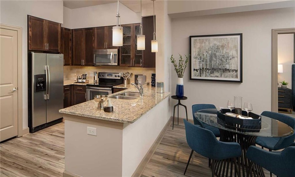 Kitchen with light hardwood / wood-style flooring, appliances with stainless steel finishes, sink, and dark brown cabinetry