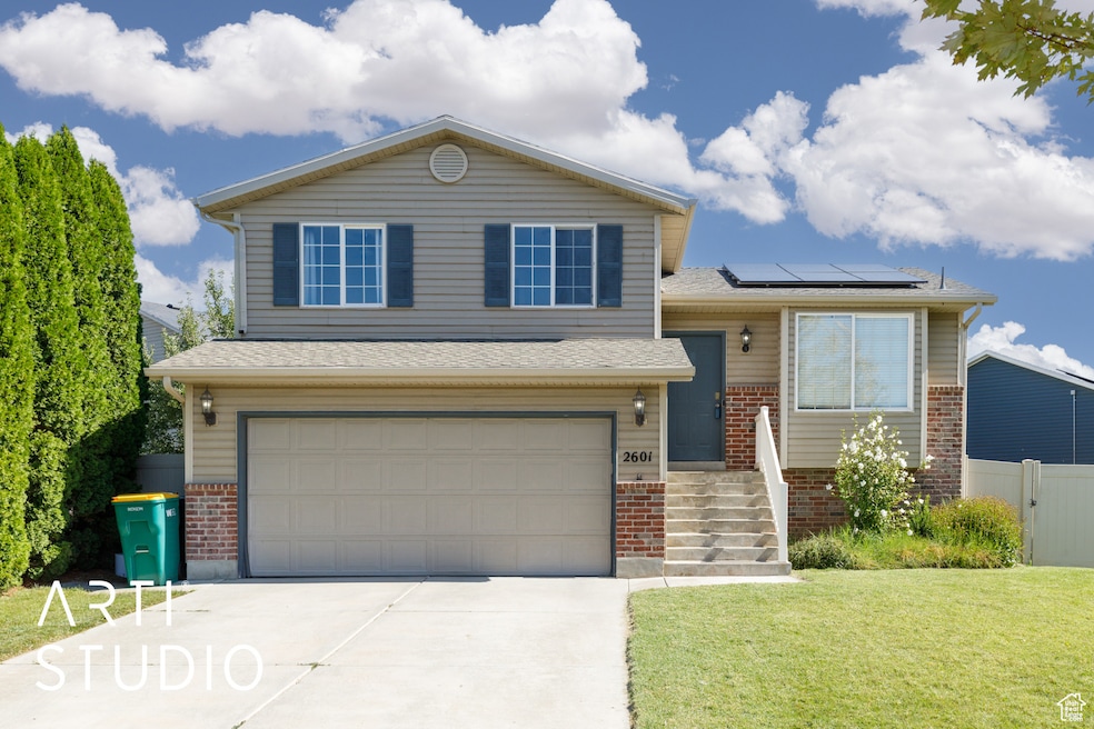View of front of house featuring brick siding, an attached garage, driveway, solar panels, and roof with shingles