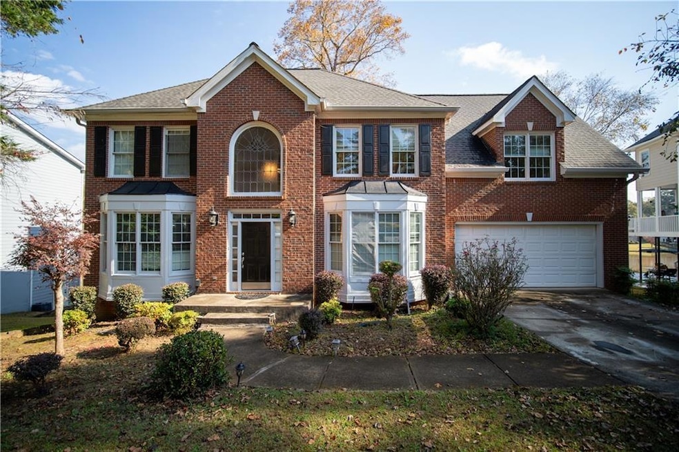 Colonial-style house with brick siding, concrete driveway, and a shingled roof