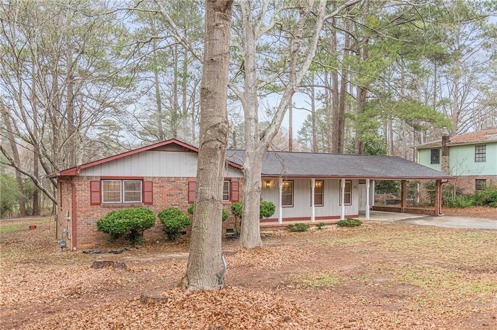 View of front facade with driveway, a porch, brick siding, and a carport