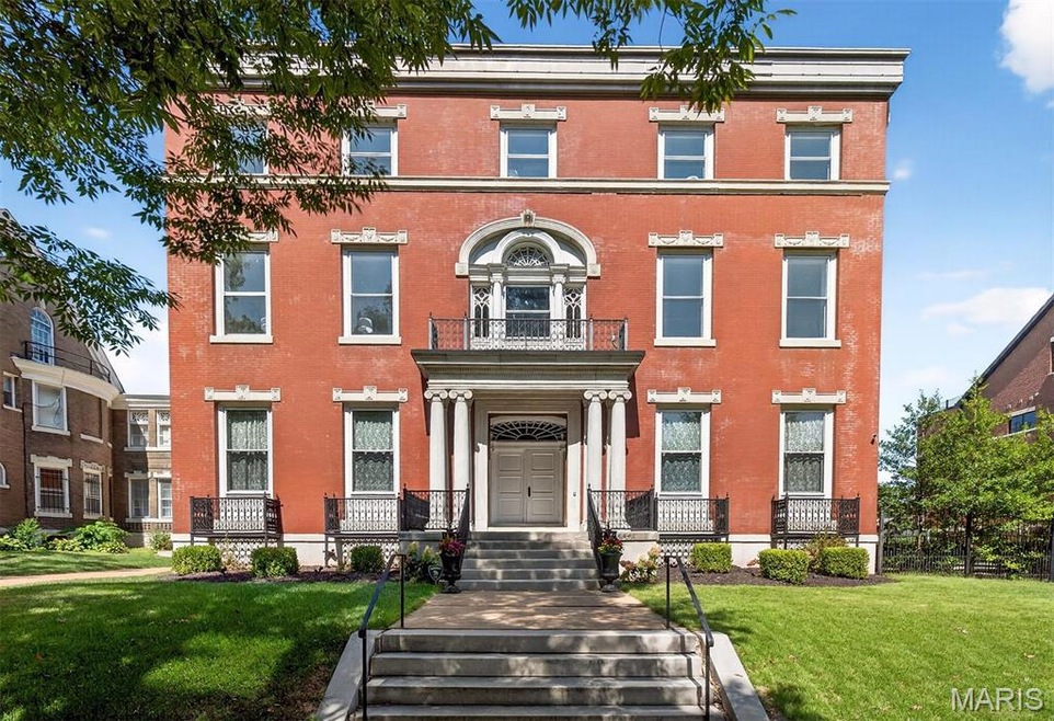 Italianate home with brick siding, a front yard, and a balcony