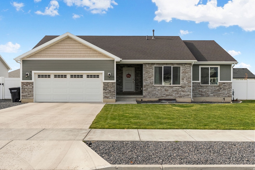 View of front facade with stone siding, concrete driveway, and an attached garage