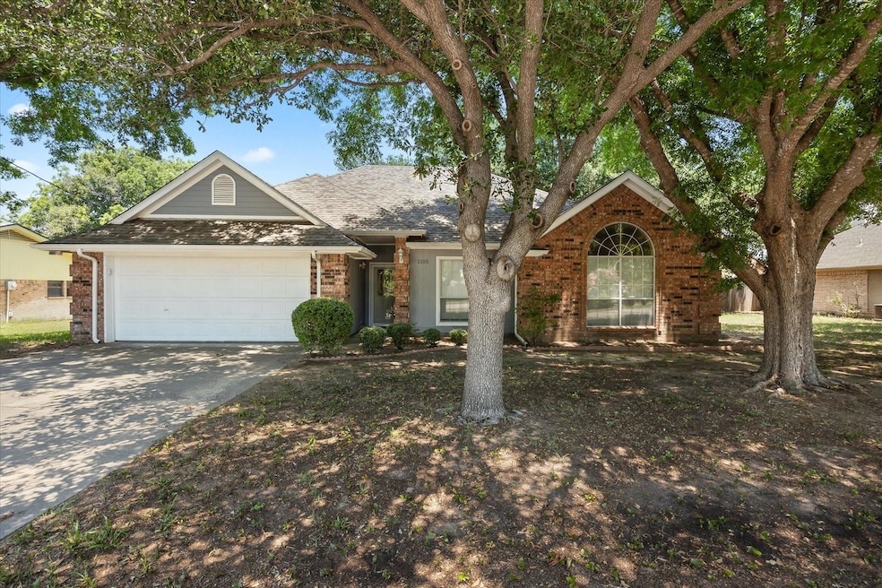 Front of home featuring a 2 car garage, large shade trees
