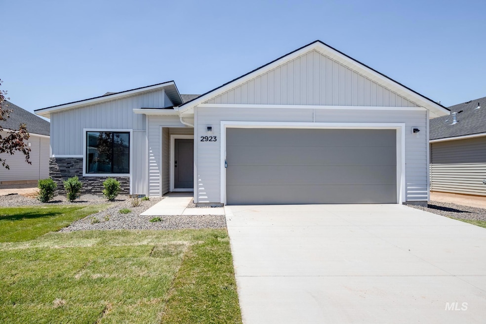View of front facade featuring a garage, concrete driveway, a front yard, board and batten siding, and stone siding