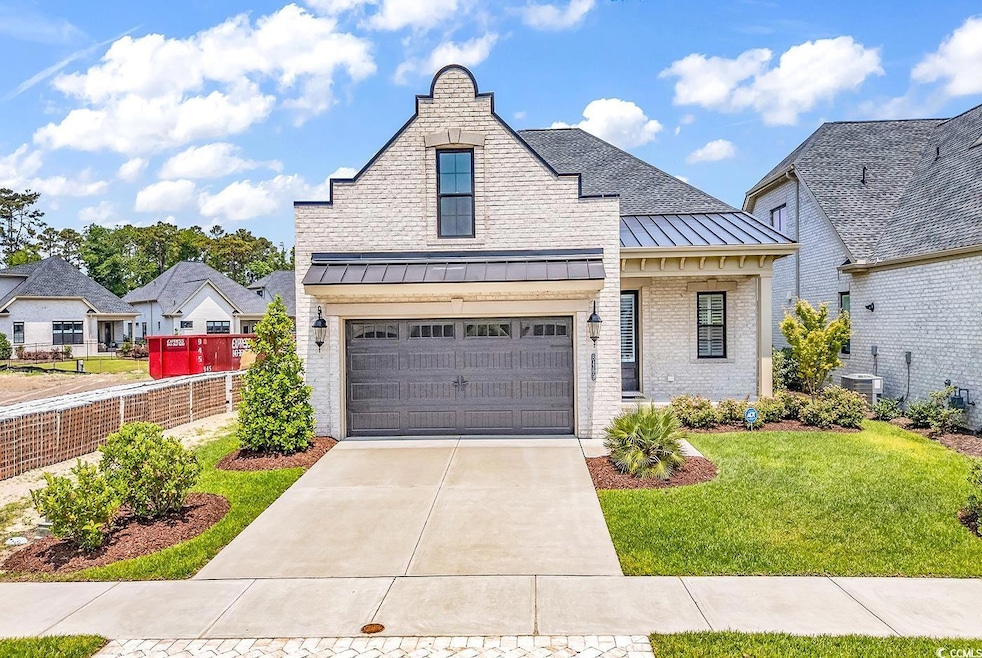 French provincial home with a standing seam roof, brick siding, a garage, concrete driveway, and central air condition unit