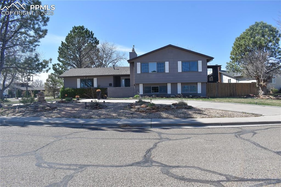 Tri-level home with a chimney, fence, and curved d
